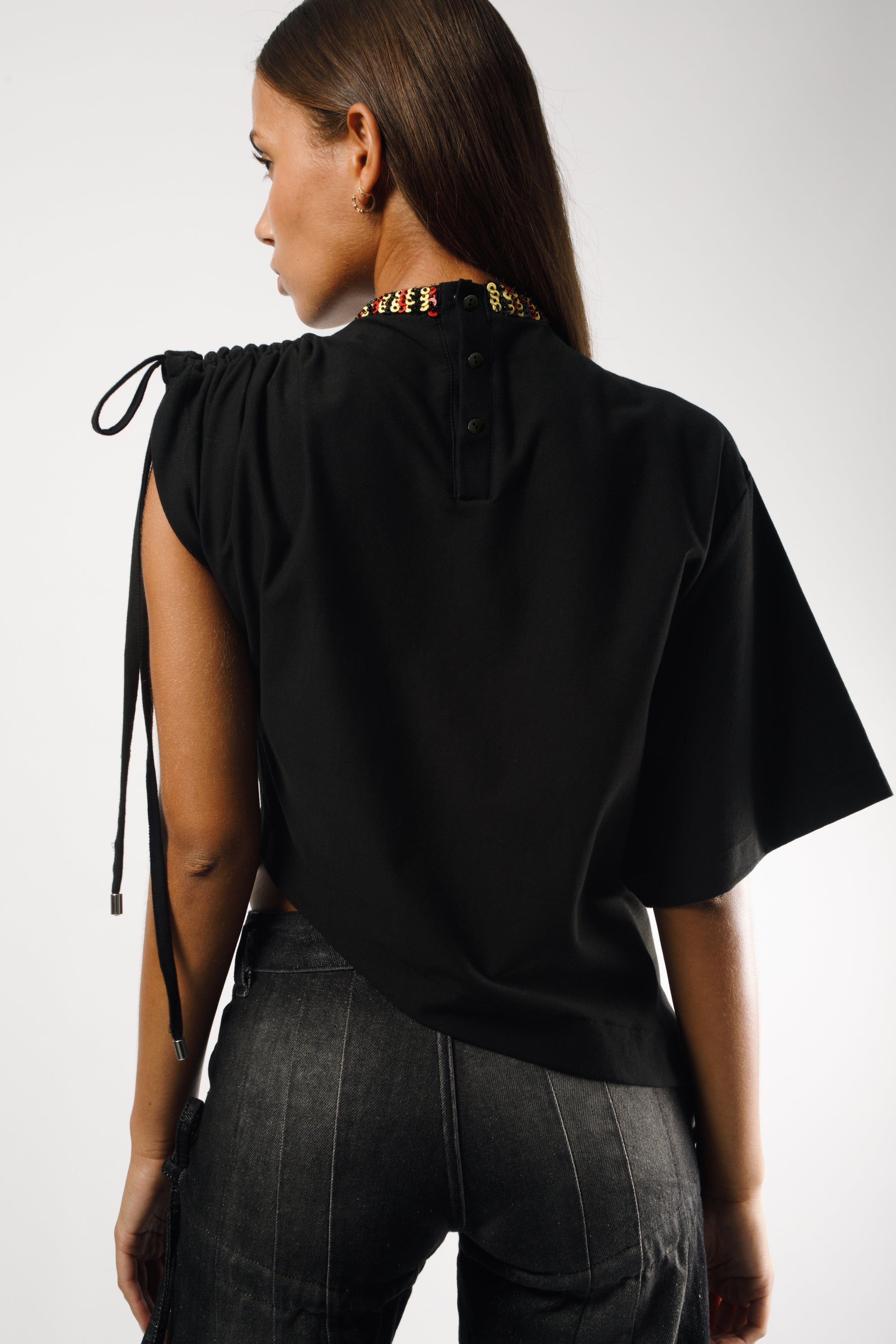 Deconstructed T-shirt with one oversized sleeve and one short sleeve, featuring adjustable cords. The collar is embroidered with rocaille pearls, handcrafted in Dakar, and black buttons on the back - back 