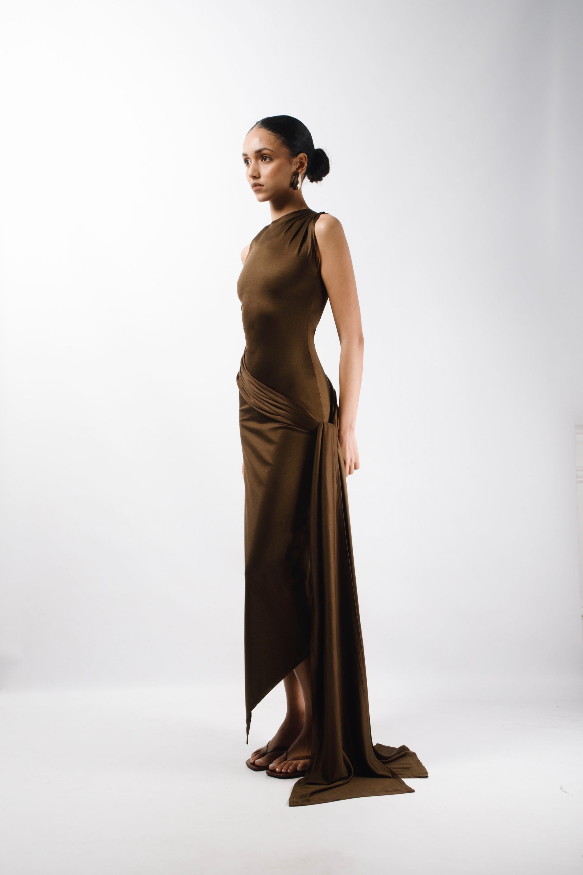 Long Asymmetric Dress in brown Gold Silk fabric with a pleated sleeve and an adjustable sleeve, the Dress features a long train attached from the waist and an opening slit that hits at the ankle - side