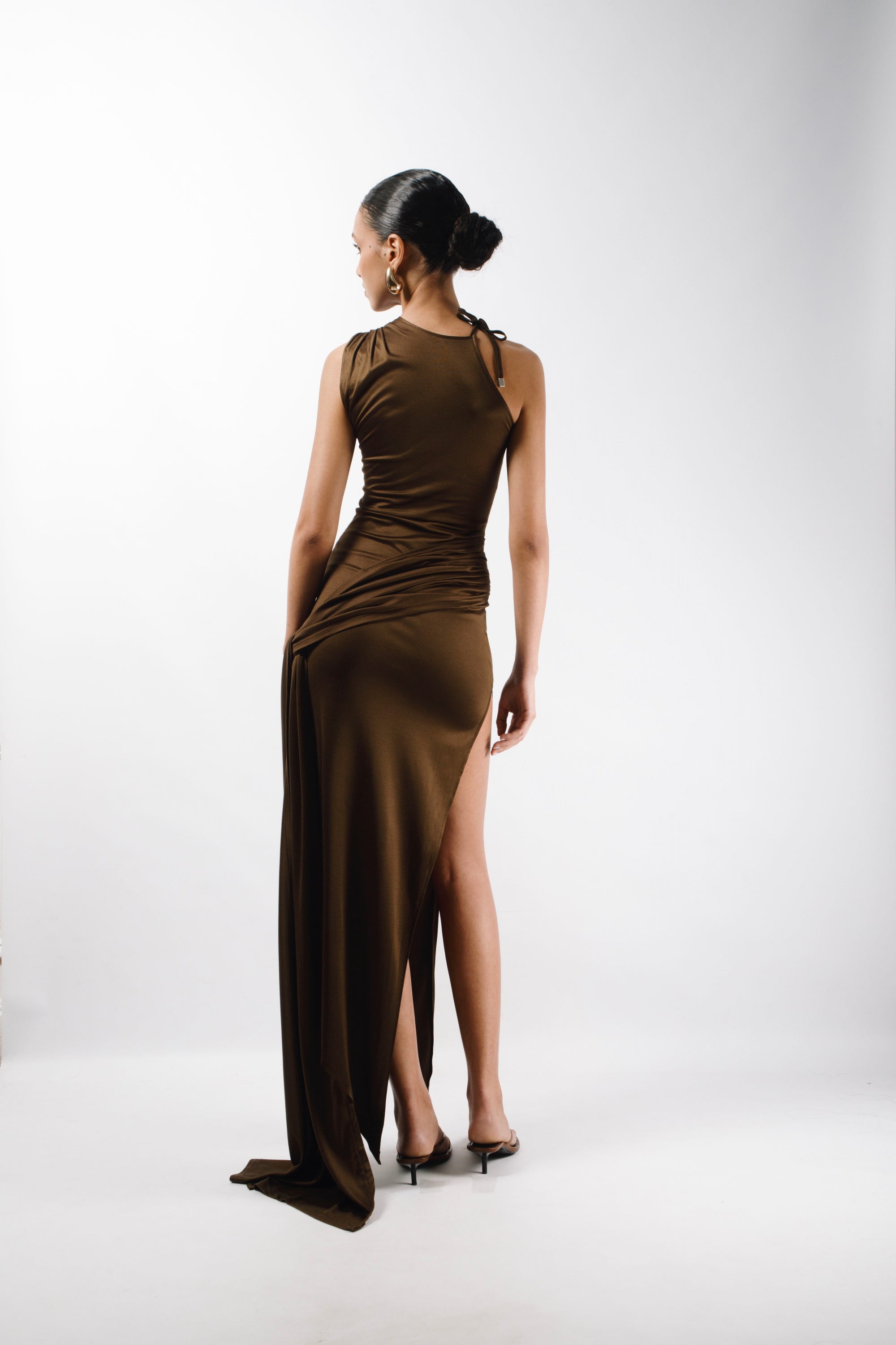 Long Asymmetric Dress in brown Gold Silk fabric with a pleated sleeve and an adjustable sleeve, the Dress features a long train attached from the waist and an opening slit that hits at the ankle - back