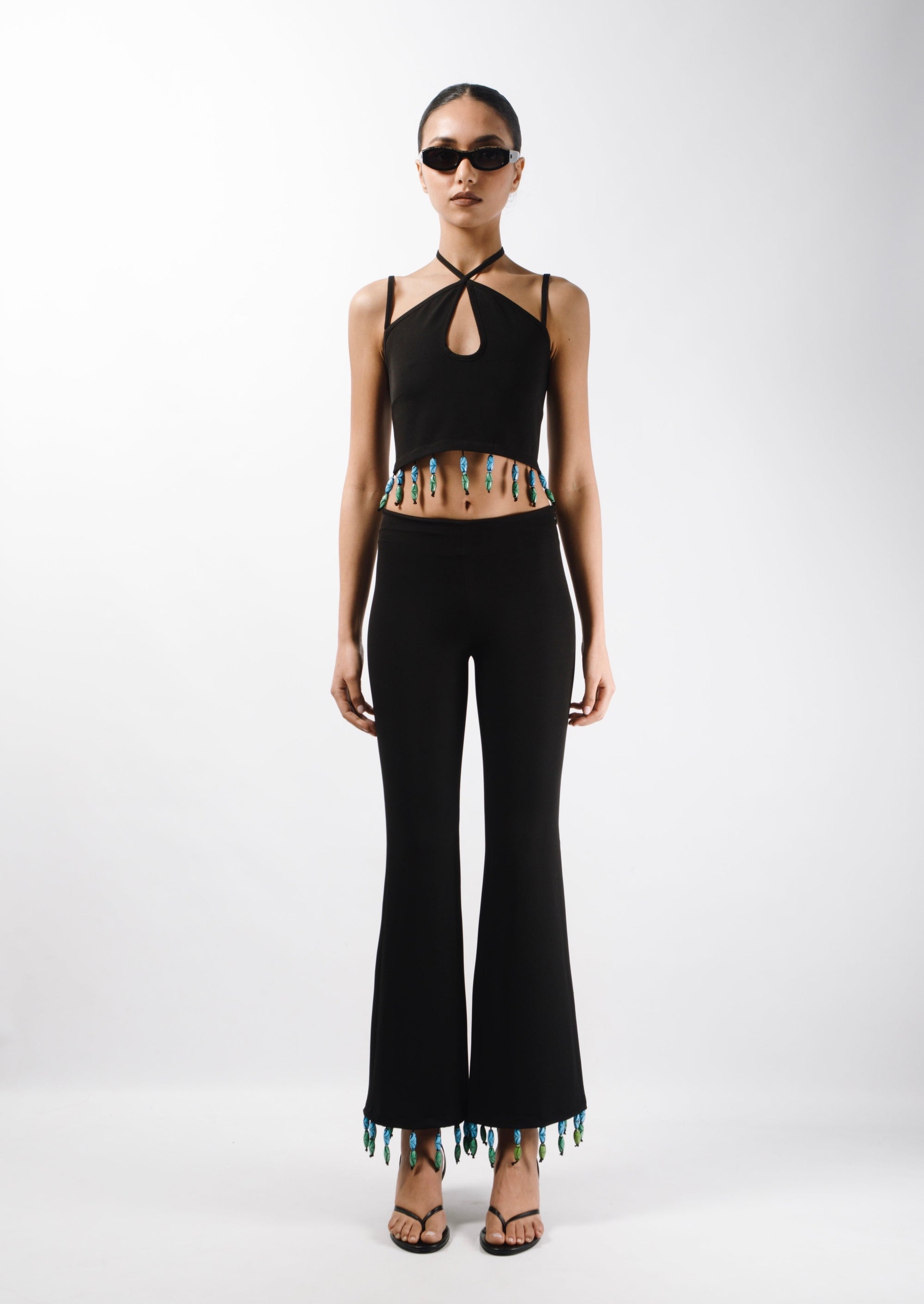 Tailored pants featuring mid rise waist and flared leg, embelished with bead fringes on the hem - front