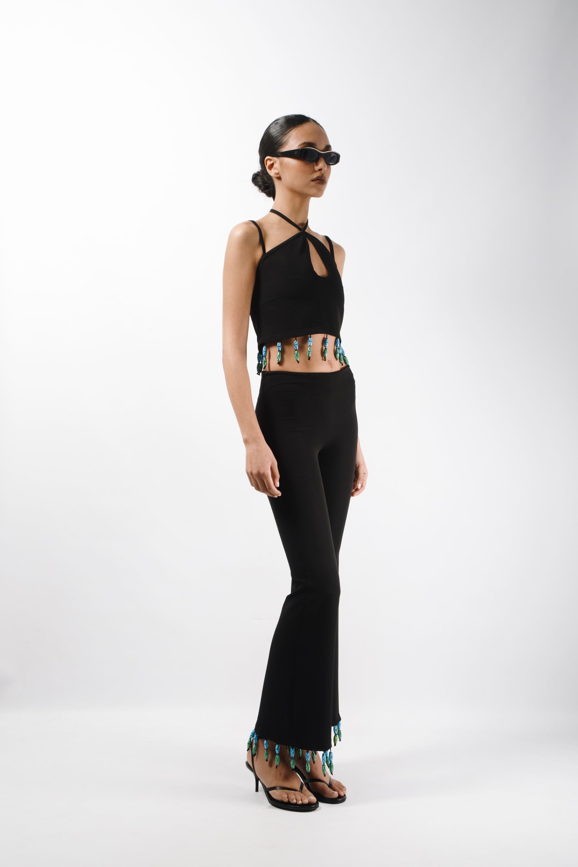 Tailored pants featuring mid rise waist and flared leg, embelished with bead fringes on the hem - side