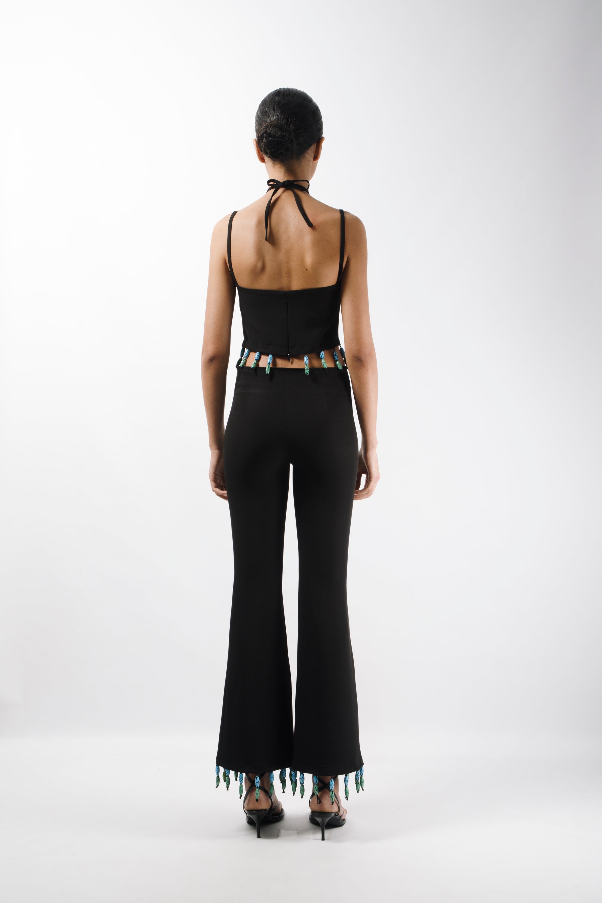 Tailored pants featuring mid rise waist and flared leg, embelished with bead fringes on the hem - back